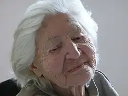 Irma Trksaks Porträt nimmt das ganze Bild ein, sie hat kurzes weißes Haar und schaut nach unten.