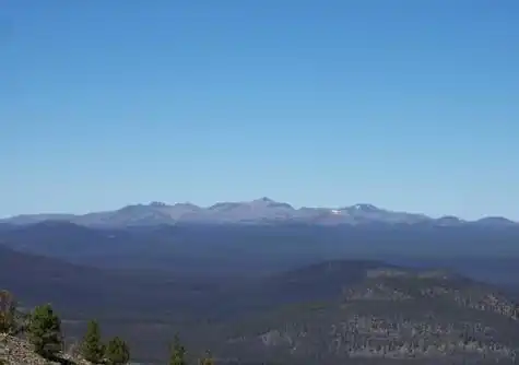Ein großer, sanft geneigter Berg ragt an einem klaren Tag über die umgebende Landschaft.