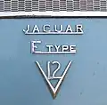 Logo eines E-Type (Serie&nbsp;III), Bj.&nbsp;1972, mit einem 5.3 ltr. Zwölfzylindermotor