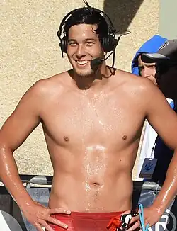 Litherland mit roter Badehose, nacktem Oberkörper und einem schwarzen Headset beim Interview