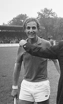 Schwarzweißfoto von Zweerts in weißer Hose und orangenem Trikot nach dem Sieg über England bei der Weltmeisterschaft 1973. Von rechts ragt ein Arm im Anzugärmel ins Bild, der zur Gratulation auf Zweerts’ Schulter klopfen möchte.