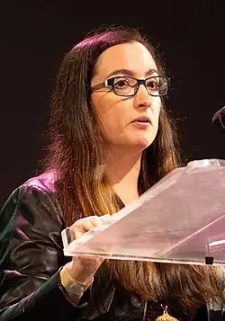 Kate Manne steht an einem Pult und hält einen Vortrag