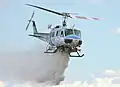 Eine Bell 205 wirft Löschwasser aus einem fest installierten Zellentank ab.