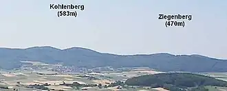 Der Kohlenberg und sein nordöstlicher Nachbar Ziegenberg (470&nbsp;m) vom Christenberg (387,4&nbsp;m) im Burgwald aus; im Vordergrund die Wetschaft-Senke mit dem 324&nbsp;m hohen, bewaldeten Kainsberg bei Münchhausen-Wollmar.