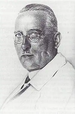 Eine schwarz-weiß Fotografie zeigt Biesalski im Porträt. Er hat einen Oberlippenbart, ähnlich wie Hitler ihn trug, kurzes Haar und trägt eine runde Brille