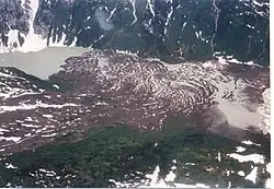 Braune Felsen liegen in einem vergletscherten Tal mit einem kleinen See auf der linken Seite.