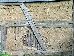 Lehmausfachungen, oben mit Lehmsteinen, unten mit abgewittertem Lehmbewurf und freigelegter Stakung