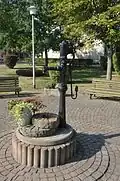 Schwengelpumpe bei der Kirche mit zwei kleinen Waidmühlsteinen