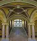 Eingangshalle mit Marmortreppe, Säulen und dem Glasfenster der Bäckerinnung