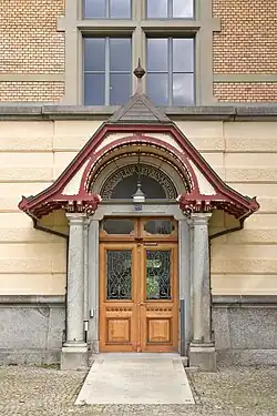 Hauptportal des Bundesamtes für Lebens­mittel­sicher­heit und Veterinär­wesen in Liebefeld, Köniz, Schweiz – imitierte Kämpfer am Stock. Die Oberlichte setzt rein ästhetisch an.