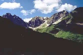 Sechszinkenspitze (Felsgipfel am linken Bildrand) von Nordosten, vom Weg aus dem Wildental zur Fiderepasshütte. Weitere Felsgipfel von links nach rechts: Mindelheimer Köpfle (Spitze links der markanten Scharte), Angererkopf (Felsgipfel in Bildmitte mit dem kleinen Felskopf rechts daneben), Liechelkopf (der höchste Felsgipfel).