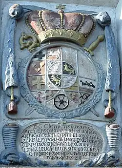 Wappenstein von Clemens August als Fürstbischof, umgeben von der Collane des Michaelsordens, darunter sein Titel in Latein, an der Westerloher Mühle in Delbrück