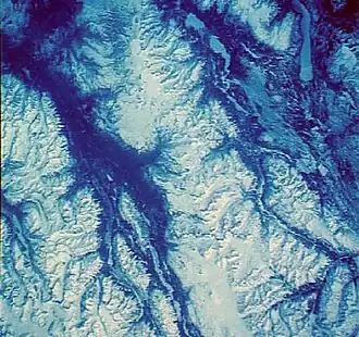 Der Mount Edziza erscheint im oberen Bildbereich westlich der schneebedeckten Seen Nuttlude Lake und Kakiddi Lake. Die schneebedeckten Berge rechts in der Mitte, zwischen den Einzugsgebieten von Mess Creek (links) und Little Iskut River (rechts) gelegen, gehören zur Spectrum Range.