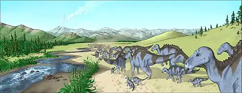 Eine Herde adulter und subadulter Maiasaura läuft einen Fluss entlang. Im Hintergrund steigt aus einem Vulkan Rauch empor