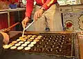 Wenden der Poffertjes nach der Hälfte der Backzeit