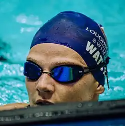 Marie Wattel hat nach einem Rennen noch die Schwimmbrille auf. Die blaue Bademütze trägt in weißer Schrift ihren Nachnamen und den Namen ihrer Universität.