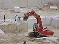 Bagger zieht Rohblock von der Wand