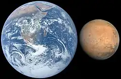 Die blau-weiße Erde und der braune Mond sind direkt nebeneinander abgebildet. Schwarzer Hintergrund.