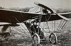 Schwarz-weiß-Foto einer Frau im dunklen Kleid mit Hut in einem Propellerflugzeug