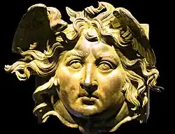 Apotropäische Verzierung (Gorgoneion) in Form eines Medusenhaupts, das am Kopfende eines Holzbalkens an der Vorderseite angebracht war