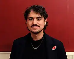 Porträt von Mehmet Akif Büyükatalay vor roter Wand, er schaut direkt in die Kamera