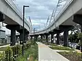 Hochbahnstrecke, darunter rekultivierte ehemalige Bahntrasse mit Radweg und Begrünung