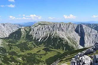 Blick vom Fölzkogel nach Osten über die Fölzalm auf die Westseite der Mitteralm. Rechts mit Schlagschatten markant vorspringend die Schartenspitze (1747 m), darüber der Kleine Winkelkogel (1918 m) unmittelbar links davon der Große Winkelkogel (1957 m). Nach links hinten steigt das Plateau zum Kampl (1990 m) an.