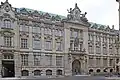 Kardinal-Faulhaber-Straße 10. Westflügel, monumentaler Neubarockbau, bez. Emil Schmidt 1895–1896, mit reichem plastischem Schmuck von Hugo Kaufmann