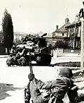 Amerikanische Infanterie sucht Deckung hinter Panzerfahrzeugen