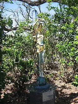 Skulptur Civitas von Audrey Flack im New Orleans Museum of Art Sculpture Garden im City Park – eine bronzefarbene Statur einer Frauengestalt mit erhobenen Armen, einen Kristall oder Eisblock in ihren Händen tragend