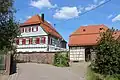 Pfarrgehöft von 1804 mit Fachwerkscheune (seit 1965 Gemeindezentrum „Schwalbennest“)[67][69]