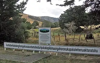 Schild mit Namen, Hügel im Hintergrund
