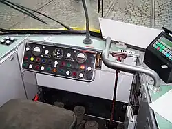 Führerstand A des O-Wagens 111 der Straßen­bahn Frankfurt am Main (DUEWAG 1969), typisch für Straßen­bahn­trieb­wagen ist das mit­geführte Weichen­stelleisen, zu sehen als senkrechter Stab mit oben querliegendem Haltegriff rechts neben dem Bedienpult.