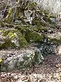 Brunnenstein mit Eingang zur Brunnen­höhle direkt hinter dem vorderen Felsstück