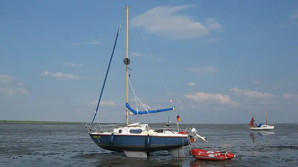Eine kleine Segelyacht, Typ Kimmkieler und eine Jolle, trockengefallen bei Schiermonnikoog
