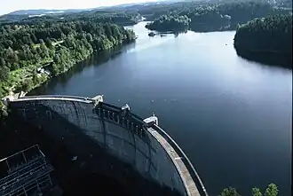 Luftbild von Staumauerkrone und See; links unten das Umspannwerk, das über dem Krafthaus liegt