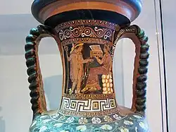 Namenvase aus Grab 69 in Licinella: Aphrodite zwischen zwei Eroten (rechts); Hermes steht vor einer sitzenden Frau mit einer Kiste in der Hand (links)