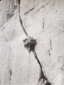 Preuß in einer Wand, wie er in einem Riss klettert, er ist nur von hinten zu sehen