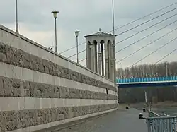 Deichmauer mit Pegelturm, im Hintergrund Raiffeisenbrücke