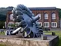 Wasserturbinenrad (Pelton Wheel) vor der stillgelegten Aluminiumhütte