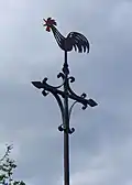 Piesbach, Turmhahn der ehemaligen barocken Kapelle innerhalb einer Grünanlage, die am Standort der ehemaligen Kapelle angelegt wurde