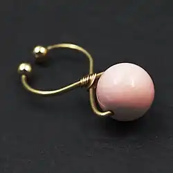 Detailansicht einer goldenen Klitoris-Klammer mit pinker Perle