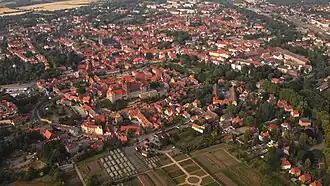 Luftaufnahme der Altstadt von Quedlinburg mit dicht stehenden Fachwerkhäusern, historischen Gebäuden und umgeben von grünen Flächen und Feldern