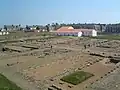 Blick vom Westtor auf das Grabungsgelände und die rekonstruierte Kaserne, dahinter das Praetorium