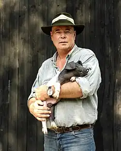 Initiator der Bäuerlichen Erzeugergemeinschaft: Rudolf Bühler. Er hält ein Ferkel auf dem Arm. Dabei handelt es sich um die fast ausgestorbene Rasse des Schwäbisch-Hällischen Landschweins.