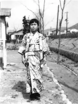 Sadako Sasaki steht in einer kargen Landschaft und blickt ohne zu lächeln in die Kamera