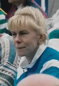 Sanna Hernesniemi sitzt auf der Tribüne. Sie trägt einen blau-weißen Trainingsanzug.