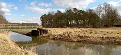 Gelände der Sassenburg innerhalb des Waldstücks mit der Aller und Brücke