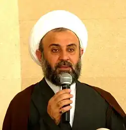 Scheich Nabil Qaouk. Porträt eines älteren arabischen Mannes mit weißem Turban und Gelehrtenumhang.