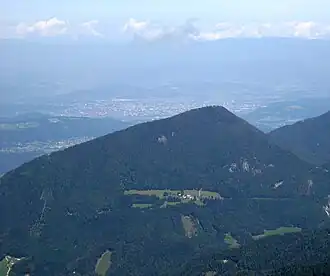 Sinacher Gupf von Süden, an der Flanke die obersten Höfe von Strugarjach, im Hintergrund Klagenfurt